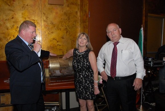 Chairman Laurence McGrath and Raffle Chair Jimmy McGonagle look on as 2012 Damian Meehan Award winner Annie O'Donnell draws the winning raffle ticket at the 2012 Donegal NY Football Banquet.