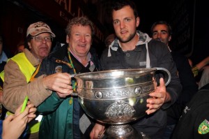 Sam Maguire arrives in Carndonagh the hometown of Leonard Harkin, who traveled from Melbourne Australia with his wife Peggy to witness this historic occasion: Sam is back in the hills of Donegal. A cherished memory for Leonard holding the Sam Mcguire Cup with Donegal captain Michael Murphy & manager Jim Mc Guinness in the background. (The brains behind their success.)