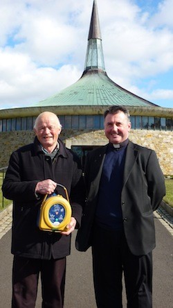 Henry presents the defibrillator to Fr Sweeney at St. Aengus', Burt.