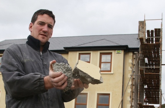 Damien Mc Cauley demonstrates how weak the blocks are from his house built in 2006 . all the outer walls have to be replaced at his family home, and his family had to be moved out. Photo Brian McDaid