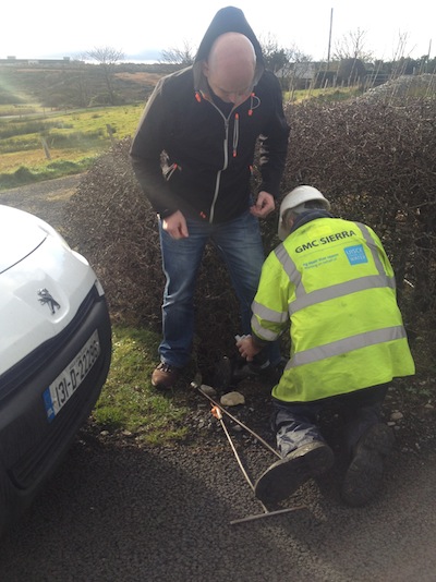 Cllr Mac Giolla Easbuig stands on a water meter as it is installed today.
