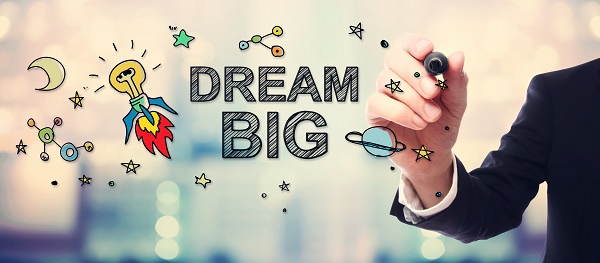 Businessman drawing Dream Big concept on blurred abstract background