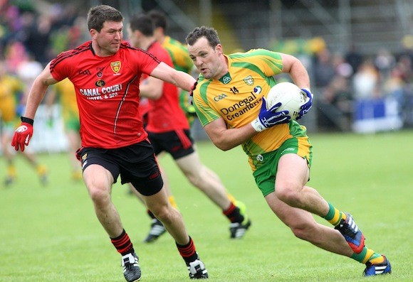 Michael Murphy on the way to one of his five points despite the challenge of Peter Turley of Down