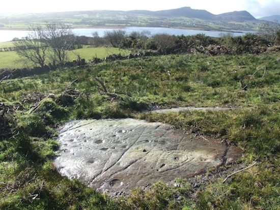 Photo 1 caption: The rediscovered rock art panel at Maghernaul, Isle of Doagh with Trawbreaga Bay in the background.