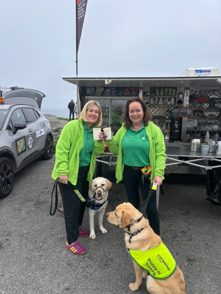 Image description: Two females smiling with Labradors wearing harnesses